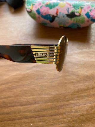 Gafas de sol ovaladas doradas y marrones versus