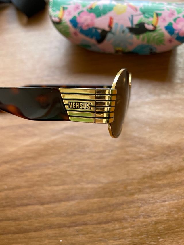 Gafas de sol ovaladas doradas y marrones versus