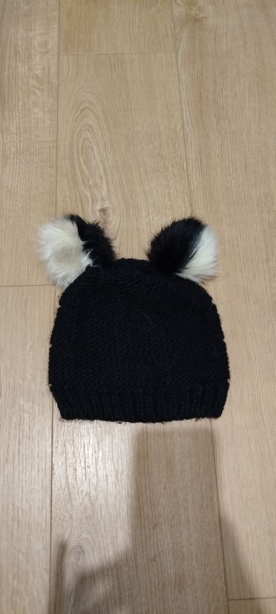 Gorro negro con dos pompones blancos y negros.