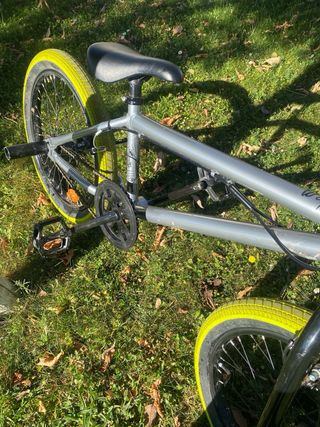 Bicicleta BMX plateada con ruedas verdes