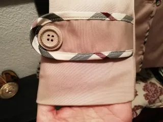 Gabardina camel con forro, y ribetes de adorno.