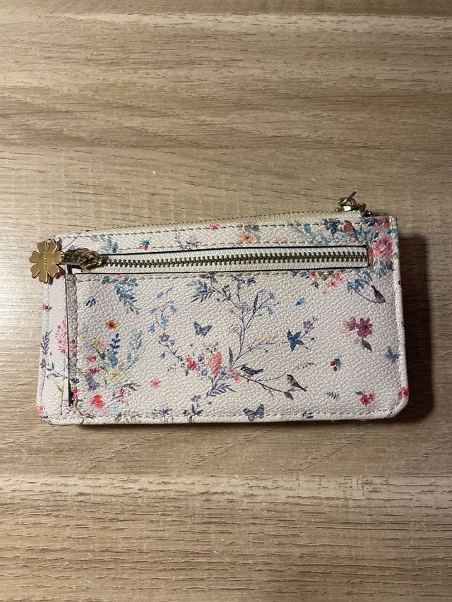 Cartera floral con cremallera y broche.