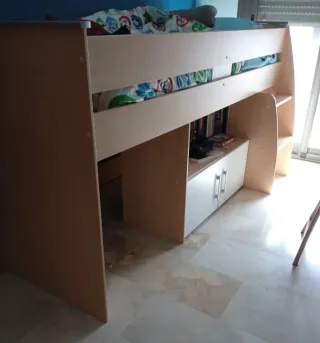 Cama infantil elevada con cajones y escritorio.