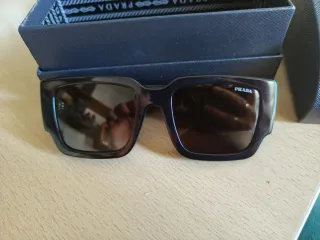 Occhiali da sole Prada neri con logo color oro.