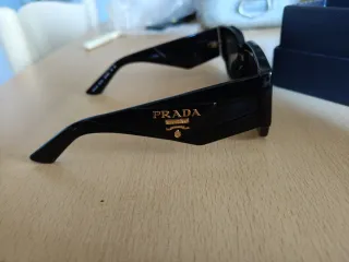 Occhiali da sole Prada neri con logo color oro.