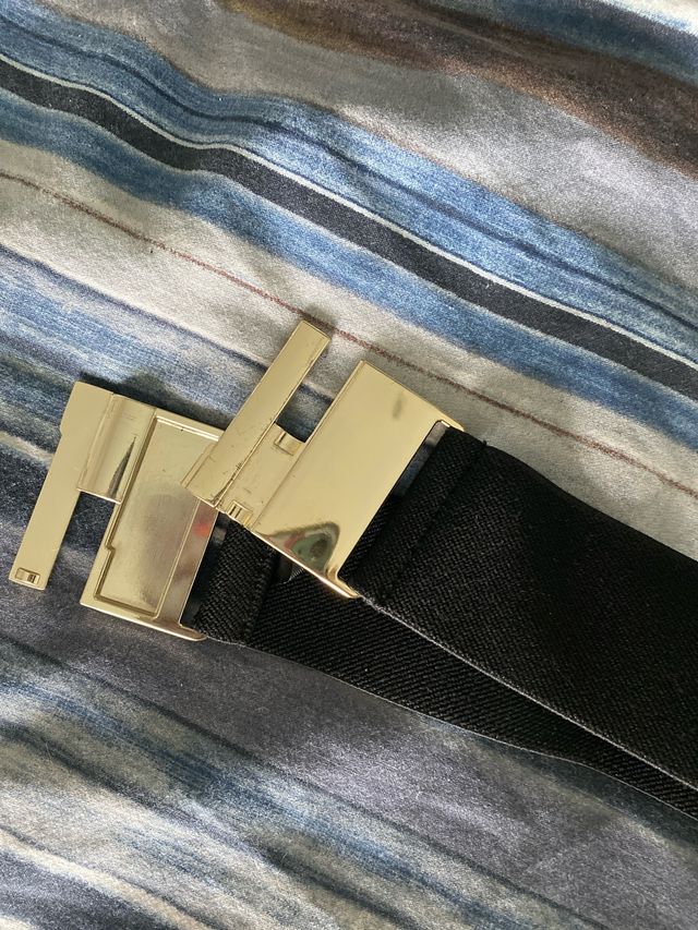 Cinturón elástico negro hebilla dorada.