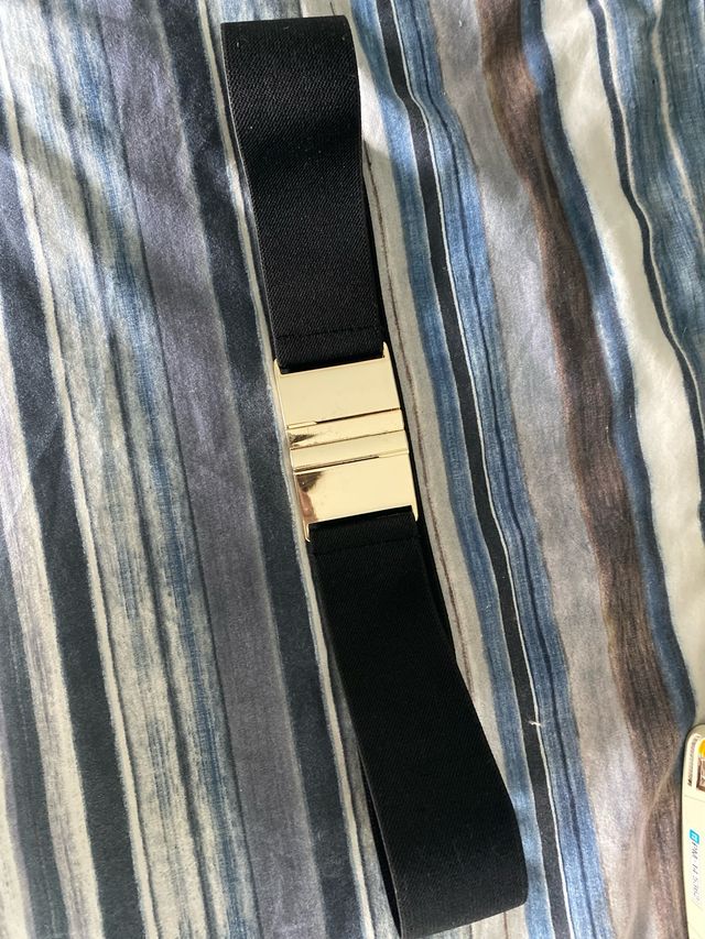 Cinturón elástico negro hebilla dorada.