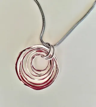 Collar largo plateado con colgante.