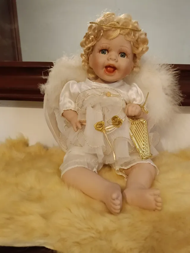 Angelito de porcelana con alas de plumas.