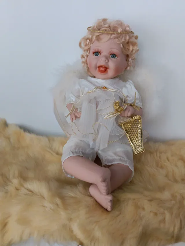 Angelito de porcelana con alas de plumas.