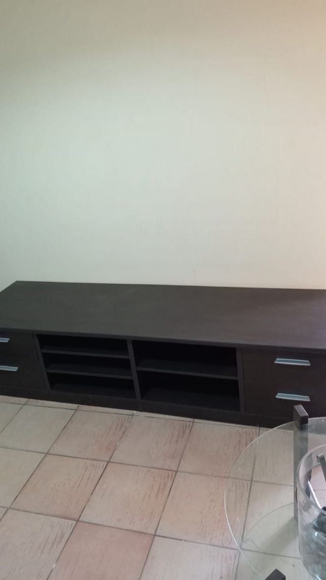 Móvel de TV escuro com gavetas e prateleiras
