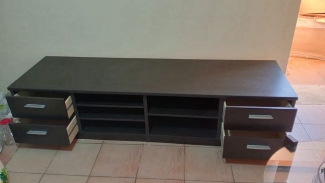 Móvel de TV escuro com gavetas e prateleiras