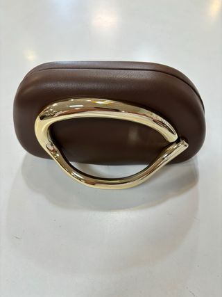 Bolso de mano marrón con asa dorada