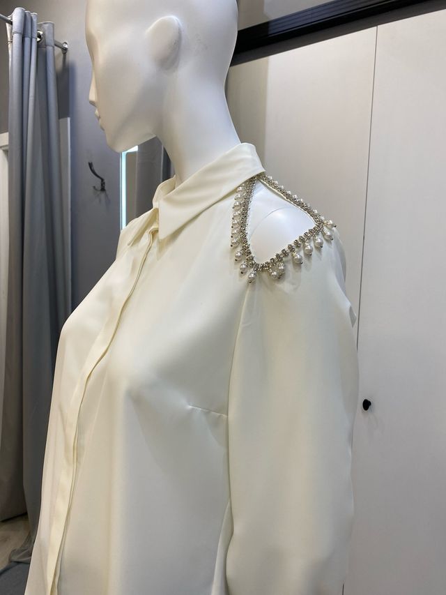 Blusa color crudo con adornos plateados y perlas.