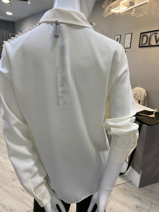 Blusa color crudo con adornos plateados y perlas.