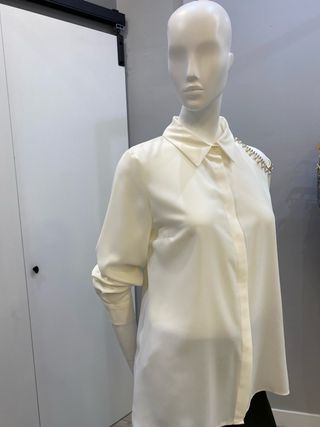 Blusa color crudo con adornos plateados y perlas.