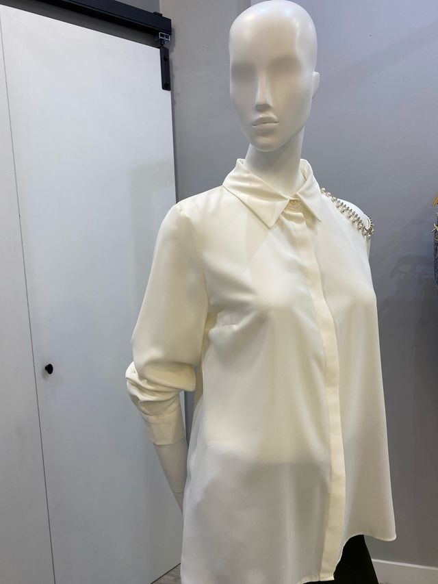 Blusa color crudo con adornos plateados y perlas.