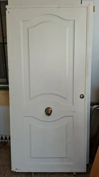 Puerta de entrada blanca,no tiene marco ni llave.