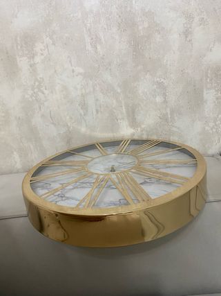 Reloj de pared dorado con números romanos