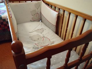 Cuna de madera con colchón y sábanas