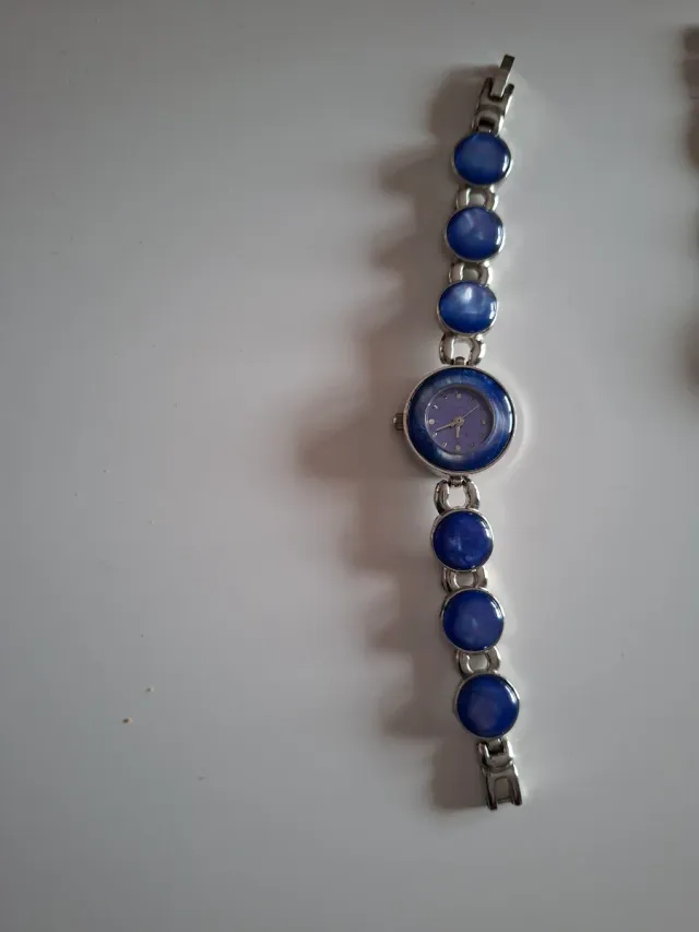 Reloj plateado con detalles azules y plateado.