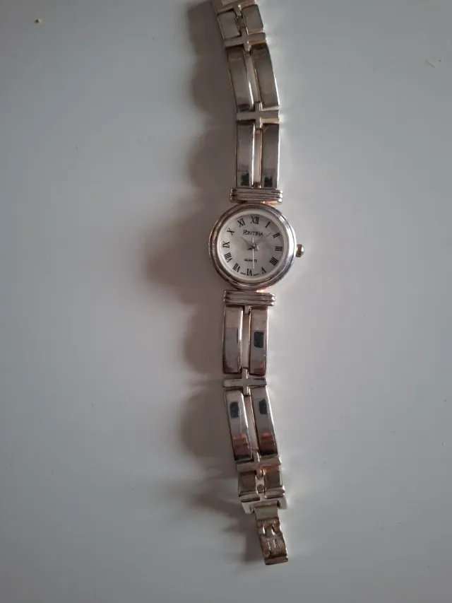 Reloj plateado con detalles azules y plateado.