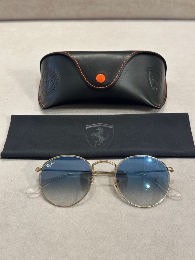 Gafas de Sol Ray-Ban doradas con cristal azul.