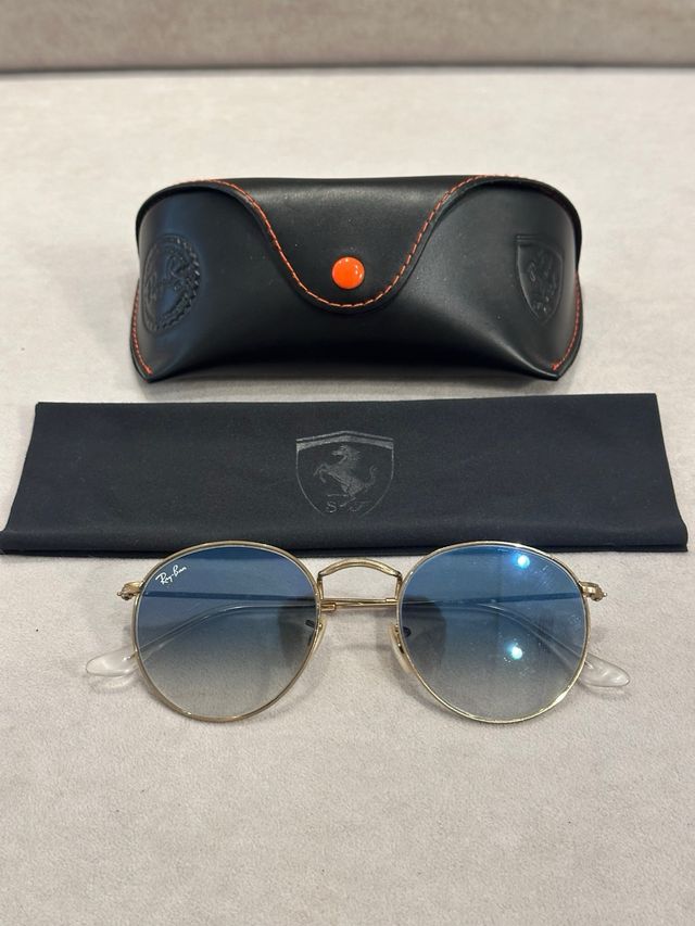 Gafas de Sol Ray-Ban doradas con cristal azul.