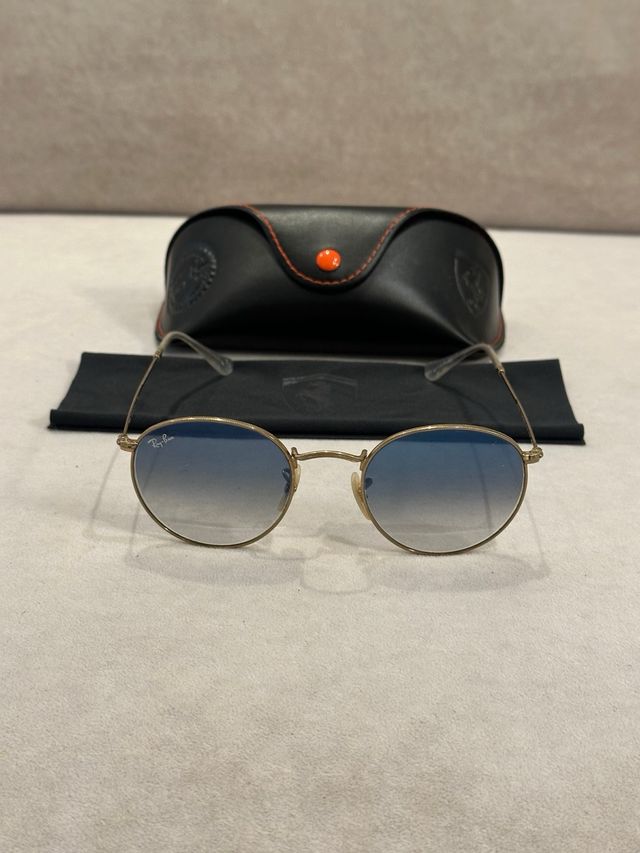 Gafas de Sol Ray-Ban doradas con cristal azul.