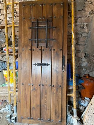 Puerta de madera rústica con ventana y reja.