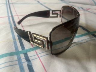 Gafas de sol Versace negras, detalle de joyas.