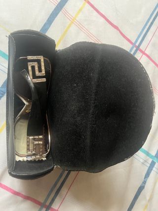 Gafas de sol Versace negras, detalle de joyas.