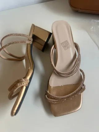 Elegantes sandalias doradas con un diseño moderno.