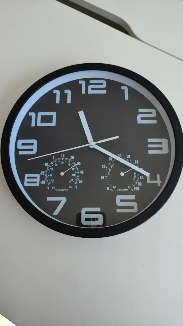 Reloj de pared negro con termómetro