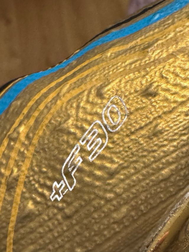 Botines de fútbol dorados y blancos