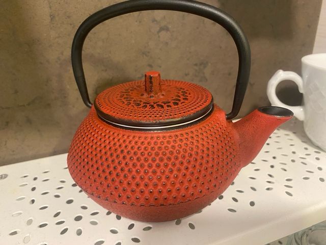 Tetera de metal roja con asa negra