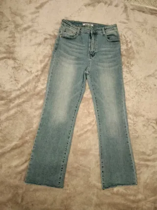 Pantalón vaquero recto azul con bajo deshilachado.