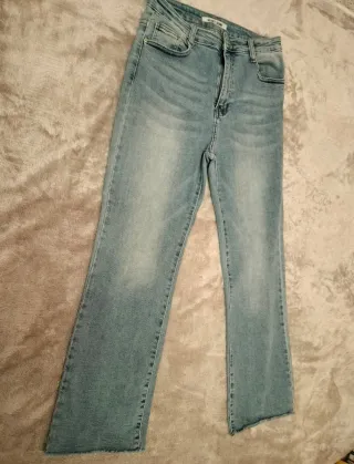 Pantalón vaquero recto azul con bajo deshilachado.