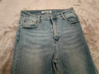 Pantalón vaquero recto azul con bajo deshilachado.