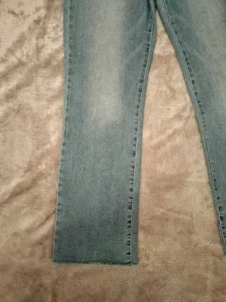 Pantalón vaquero recto azul con bajo deshilachado.