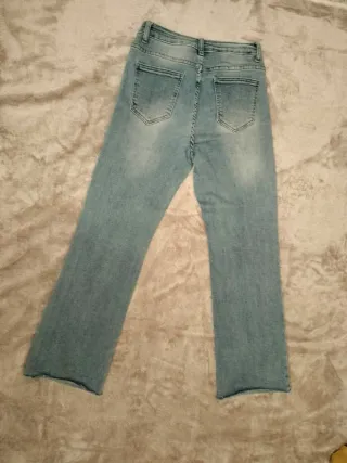 Pantalón vaquero recto azul con bajo deshilachado.