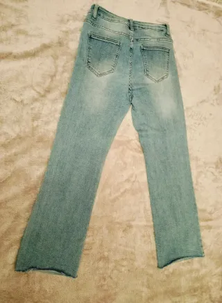 Pantalón vaquero recto azul con bajo deshilachado.