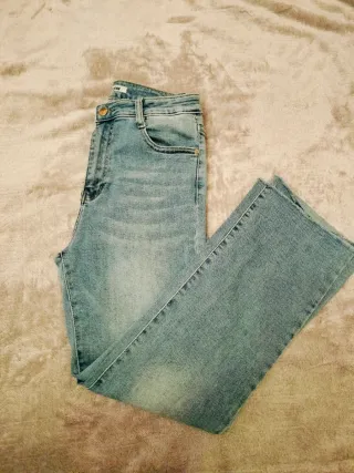 Pantalón vaquero recto azul con bajo deshilachado.