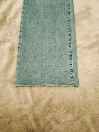 Pantalón vaquero recto azul con bajo deshilachado.