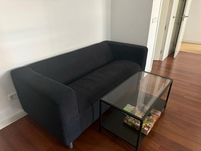 Sofá negro con mesa de centro de cristal