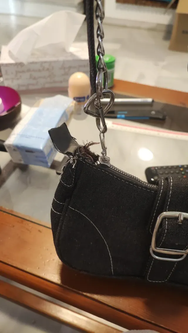 Bolso negro con cadena plateada, descosido