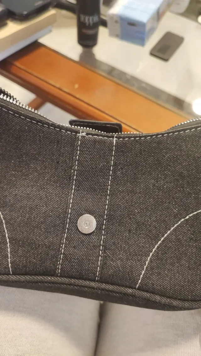 Bolso negro con cadena plateada, descosido