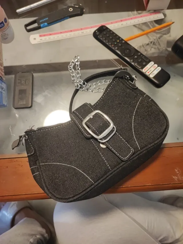 Bolso negro con cadena plateada, descosido