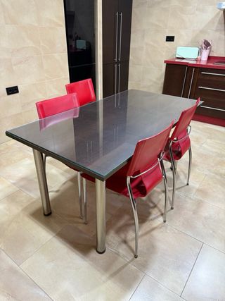 Mesa de comedor con 4 sillas rojas.