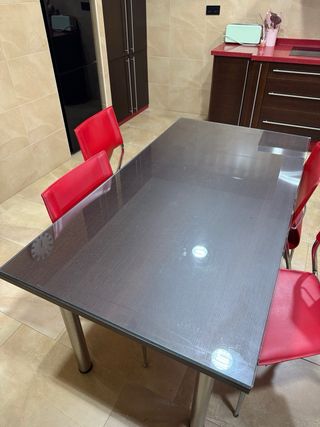 Mesa de comedor con 4 sillas rojas.